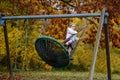 Happy child girl on swing in fall. Little kid playing in the autumn on playground, swinging and having fun. Autumnal Royalty Free Stock Photo