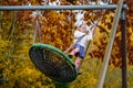 Happy child girl on swing in fall. Little kid playing in the autumn on playground, swinging and having fun. Autumnal Royalty Free Stock Photo