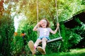 Happy child girl on swing in sunny summer garden Royalty Free Stock Photo