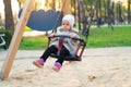 Happy child girl on swing in sunset fall. Little kid playing in the autumn on the nature park