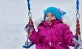 Happy child girl on swing in sunset winter. Little kid playing on a winter walk in nature Royalty Free Stock Photo