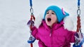 Happy child girl on swing in sunset winter. Little kid playing on a winter walk in nature Royalty Free Stock Photo