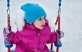 Happy child girl on swing in sunset winter. Little kid playing on a winter walk in nature Royalty Free Stock Photo