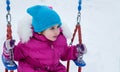 Happy child girl on swing in sunset winter. Little kid playing on a winter walk in nature Royalty Free Stock Photo