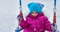 Happy child girl on swing in sunset winter. Little kid playing on a winter walk in nature Royalty Free Stock Photo