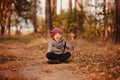 Happy child girl on the walk in autumn forest sitting on the road