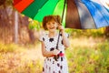 Happy child girl walk with multicolored umbrella under rain