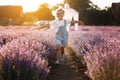 happy child girl is walking in lavender field on sunset. Smiling kid in suglasses , jeans jumpsuit is having fun in Royalty Free Stock Photo