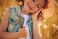 Happy child girl walking on summer meadow with dangelions. Rural country style scene, outdoor activities. Royalty Free Stock Photo