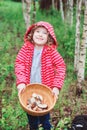 Happy child girl with wild edible wild mushrooms on wooden plate Royalty Free Stock Photo