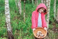 Happy child girl with wild edible wild mushrooms on wooden plate