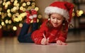 Happy child girl writing letter santa home near Christmas tree Royalty Free Stock Photo