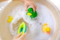 Happy child, girl 3 years old plays with rubber green, yellow ducks for swimming, plastic boat, child`s toys in soapy foam, Royalty Free Stock Photo