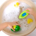 happy child, girl 3 years old plays with rubber green, yellow ducks for swimming, plastic boat, child's toys in soapy foam, Royalty Free Stock Photo