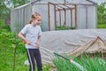 A happy child, a girl of 7-9 years, school age, watering from a watering can garden, vegetable garden, green plants in