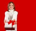 Happy child giving or receiving gift box with arms extended forward. Kid smiling and looking at camera on red background Royalty Free Stock Photo