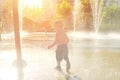 Happy child has fun playing in water fountains on hot day during summer. Boy playing in water at waterpark. A kid in spray park Royalty Free Stock Photo