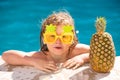 Happy child having fun at swimming pool on sunny day. Kids summer holidays and vacation concept. Summer pineapple fruit. Royalty Free Stock Photo