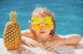 Happy child having fun at swimming pool on sunny day. Kids summer holidays and vacation concept. Summer pineapple fruit. Royalty Free Stock Photo