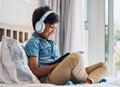 Happy, child and headphones with tablet on bed to watch funny movies, play video games or app. Boy kid laughing with Royalty Free Stock Photo