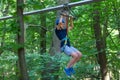 Happy child, healthy teenager in helmet enjoys activity in a climbing adventure rope park