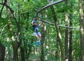 Happy child, healthy teenager in helmet enjoys activity in a climbing adventure rope park