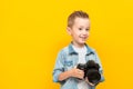 Happy child hold professional photo camera, smiles and looks at the camera Royalty Free Stock Photo