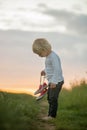 Happy child, holding pair of sneakers in hands, walking on a rural path