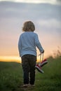 Happy child, holding pair of sneakers in hands, walking on a rural path