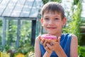 Happy child holding a pink donut in the park. The child refuses to eat healthy food. Unhealthy food concept Royalty Free Stock Photo