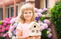 Happy child holding toy house in hands against new home. Royalty Free Stock Photo