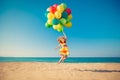 Happy child jumping with colorful balloons on sandy beach Royalty Free Stock Photo