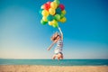 Happy child jumping with colorful balloons on sandy beach Royalty Free Stock Photo