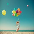 Happy child jumping with colorful balloons on sandy beach Royalty Free Stock Photo