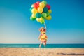 Happy child jumping with colorful balloons on sandy beach Royalty Free Stock Photo