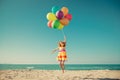 Happy child jumping with colorful balloons on sandy beach Royalty Free Stock Photo