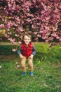 Happy child jumping outdoors. Kids fashion and trendy clothes. Spring day. Spring pink sakura blossom. Stylish boy having fun Royalty Free Stock Photo