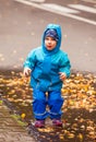 Happy child jumping in puddle in autumn time Royalty Free Stock Photo