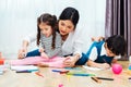 Happy child kid boy and girl son kindergarten drawing on peper teacher education with beautiful mother Royalty Free Stock Photo