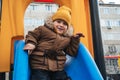 Happy child kid boy playing on a slide on playground in winter in the park Royalty Free Stock Photo