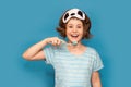 Happy child kid girl with sleeping mask brush her teeth with toothbrush in morning isolated over blue background. Health Royalty Free Stock Photo