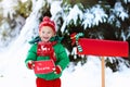 Child with letter to Santa at Christmas mail box in snow Royalty Free Stock Photo