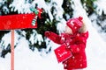 Child with letter to Santa at Christmas mail box in snow Royalty Free Stock Photo