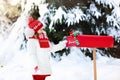 Child with letter to Santa at Christmas mail box in snow Royalty Free Stock Photo