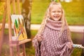 Happy child laughs. joyful little girl artist paints a picture in autumn in the park Royalty Free Stock Photo