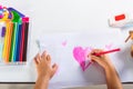 Happy child little girl colorful drawing pink heart on white paper Royalty Free Stock Photo