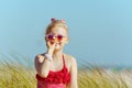 Happy child makes nose from lipstick with spf on ocean shore