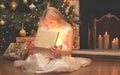 happy child opens the magic box gift with light in dark over christmas tree and fireplace home Royalty Free Stock Photo