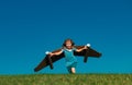 Happy child with paper wings against blue sky. Kid with toy jetpack having fun in spring green field outdoor. Freedom Royalty Free Stock Photo