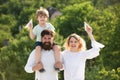 Happy child with parents playing with toy wings against summer sky background. Happy smiling boy on shoulder dad looking Royalty Free Stock Photo